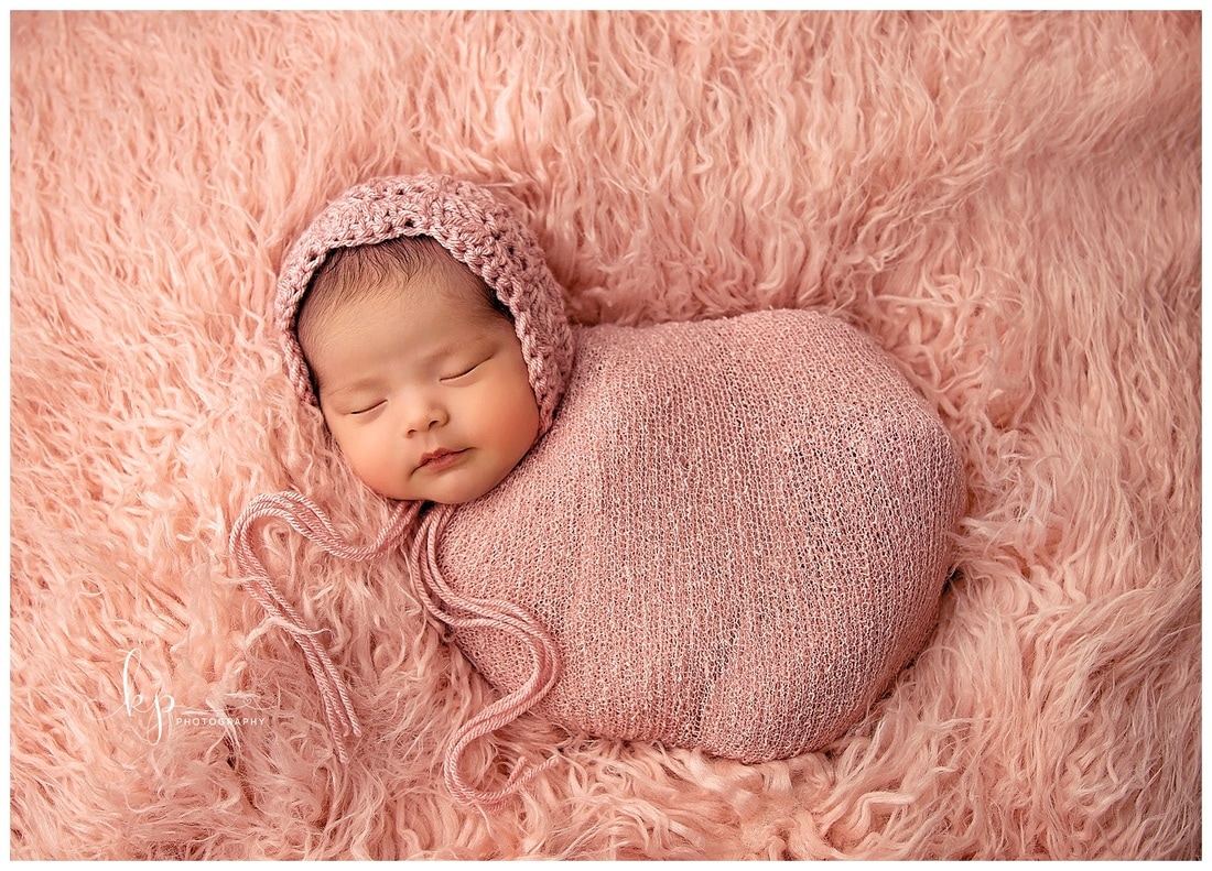 newborn baby girl in pink wrap and bonnet