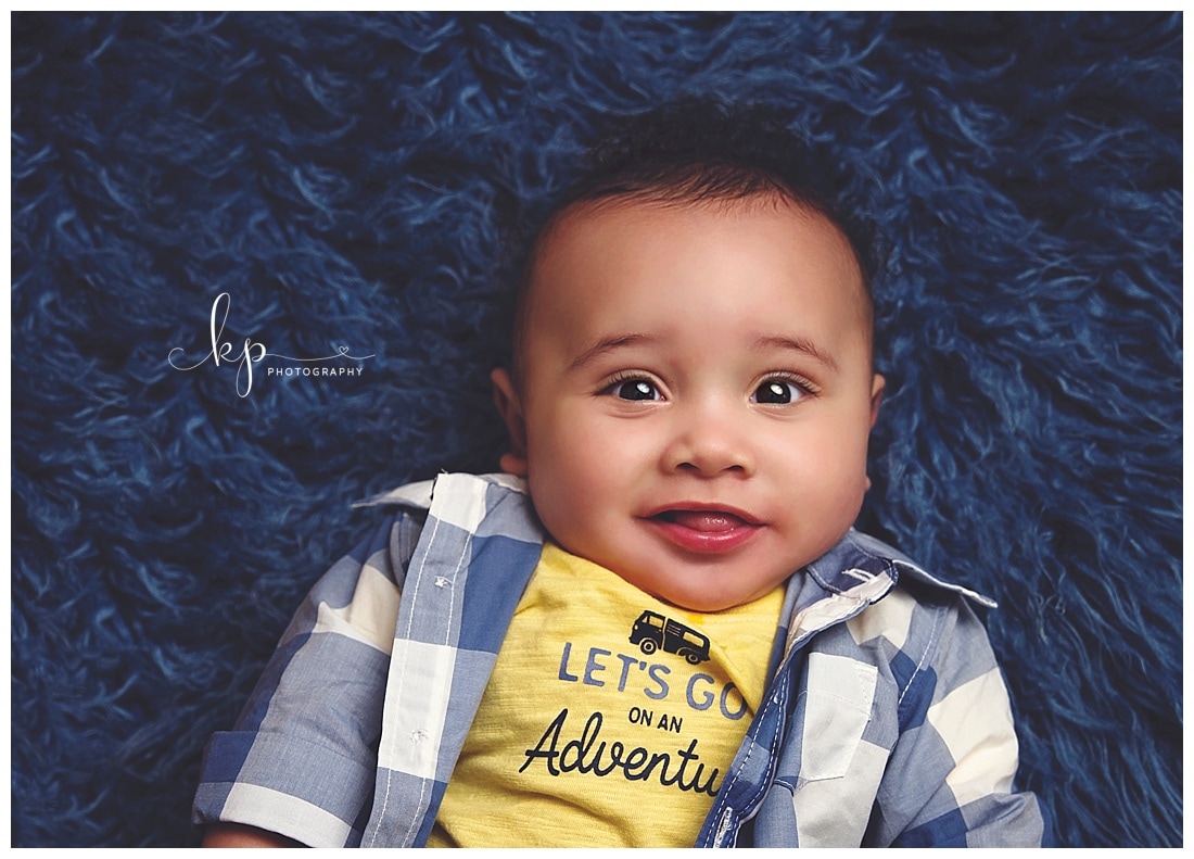 6 month old boy wearing plaid shirt on blue fur rug