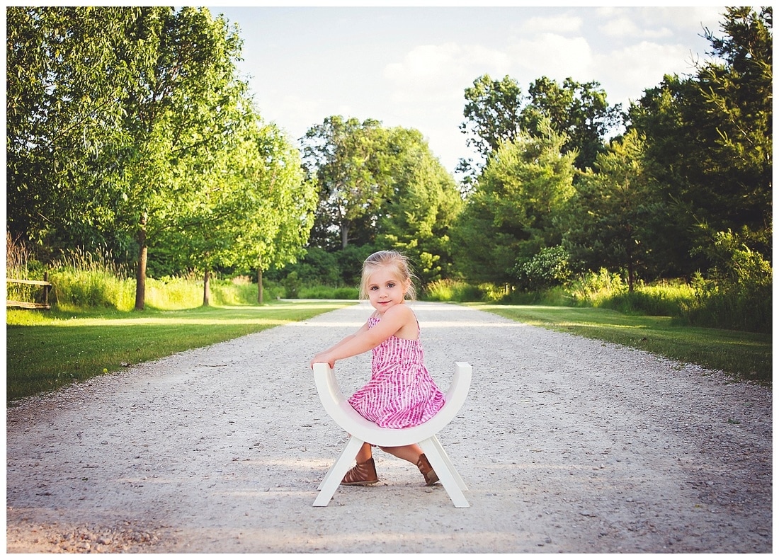 3 year old little girl photography session in green park setting in summer on gravel road