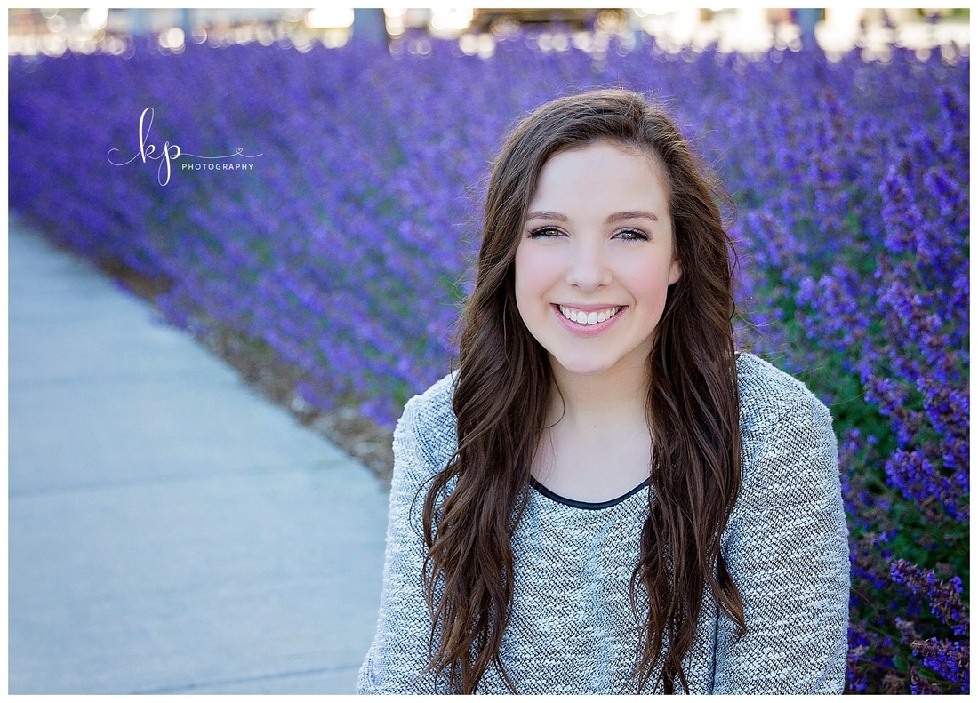 high school senior girl posing by field of purple flowers